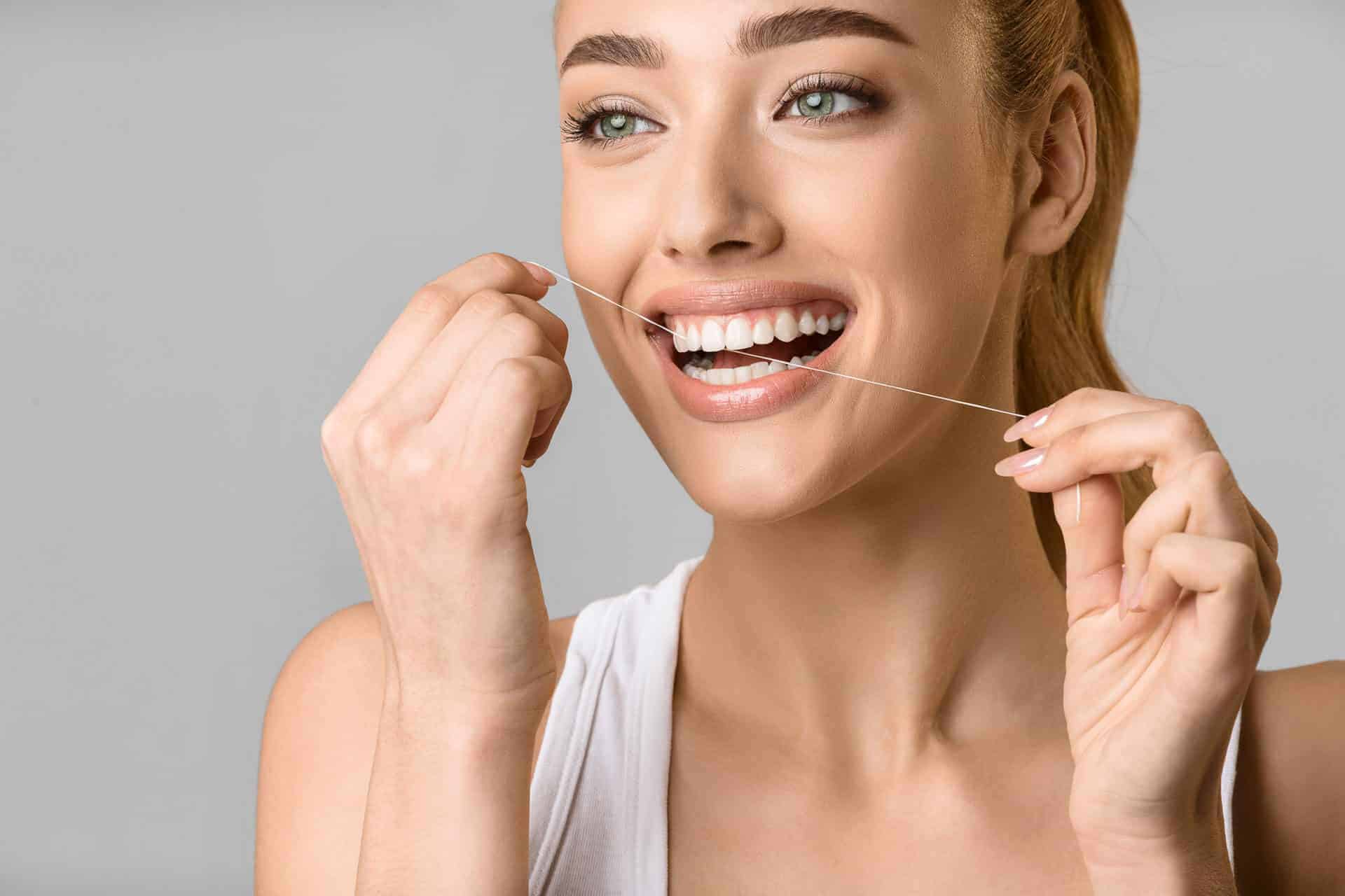 woman enjoys flossing her white teeth for her cosmetic dentistry