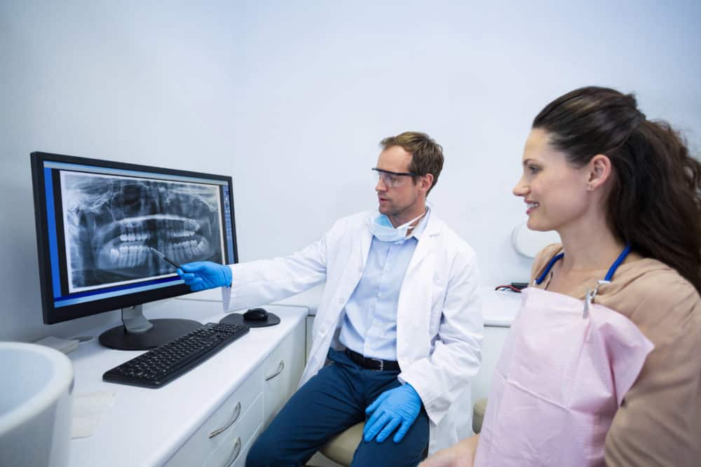 Dentist showing an x-ray of shifting teeth to female patient at dental clinic