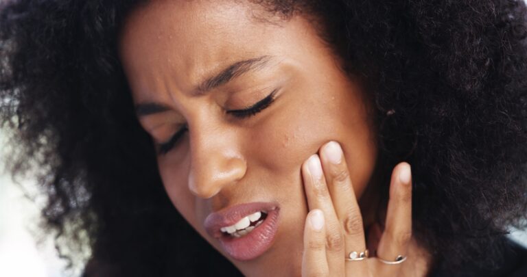 closeup of a woman suffering from tooth pain, need for a root canal